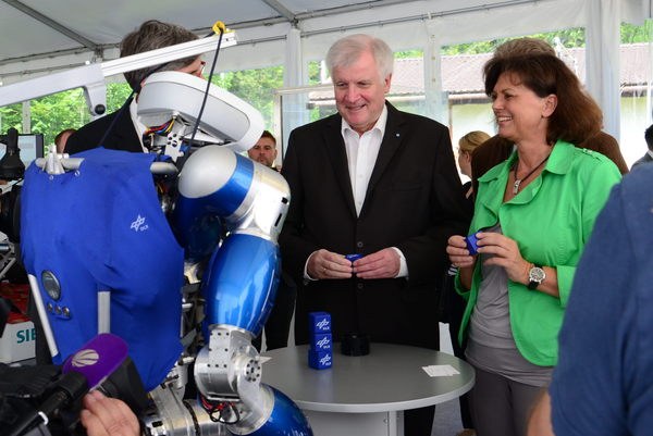Roboter TORO steht zusammen mit Alin Albu-Schäffer, Horst Seehofer und Ilse Aigner um einen kleinen runden Tisch
