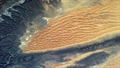 Dünen in der Sahara, umrahmt von Felsen.