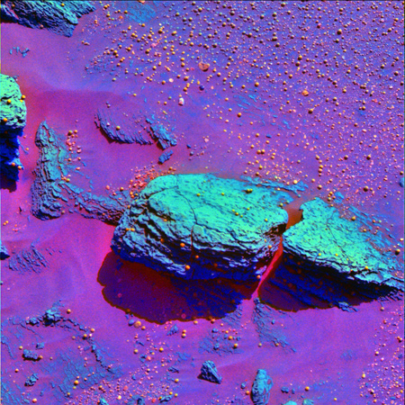 Auf dieser Aufnahme wegen der speziellen Einfärbung besonders gut sichtbar: An einigen Stellen ist das Gestein auf dem Mars von „Kügelchen“ bedeckt. Sie entstehen eigentlich nur, wenn Wasser im Spiel ist. 
Bild: NASA 
