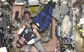 Gennady Padalka aus Russland (im Hintergrund) hilft ESA-Astronaut André Kuipers aus den Niederlanden bei einem medizinischen Versuch. Es geht dabei um den Gleichgewichtssinn. Bild: ESA