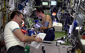 Alexander Kaleri aus Russland (links) und ESA-Astronaut Pedro Duque aus Spanien führen ein medizinisches Experiment durch. Wie man sieht, ist die ISS mit wissenschaftlichen Geräten geradezu vollgestopft: ein fliegendes High-Tech-Labor. Bild: ESA