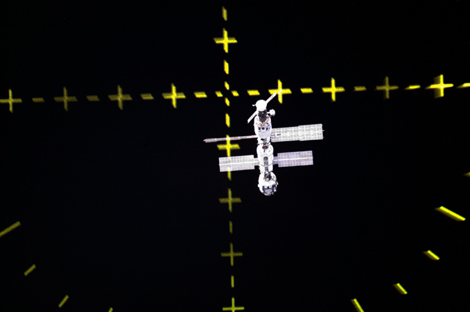 So sieht die ISS aus, wenn man sich ihr mit einem Sojus-Raumschiff nähert. Die Markierungen zeigen an, ob die Crew auf dem richtigen Kurs ist. Das Docking erfolgt in der Regel automatisch – es sei denn, die Automatik versagt: Dann steuert der Kommandant bzw. die Kommandantin das Raumschiff per Hand ins Ziel. Bild: NASABild: NASA