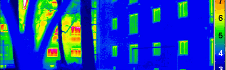 Mit einer speziellen Kamera wurde dieses „Wärmebild“ gemacht. Links ist im Hintergrund – teils von einem Baum verdeckt – ein normales Haus zu erkennen. Die roten und grünen Stellen zeigen an, wo Energie verschwendet wird. Rechts ist ein Passivhaus zu sehen – hier sind die Wände sehr gut isoliert, was man an der blauen Farbe sieht. Bild: Passivhaus Institut