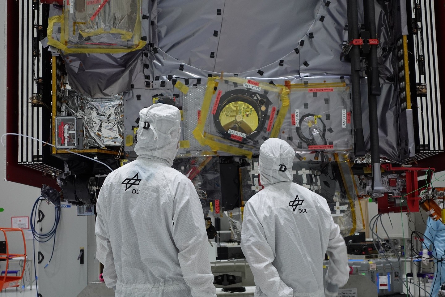 Zwei DLR-Mitarbeiter stehen im Reinraum vor dem JUICE-Satelliten.
