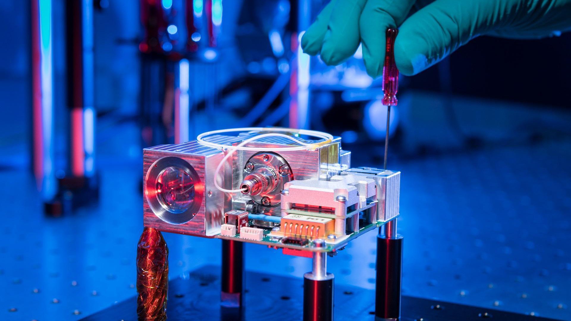 Das Flugmodell des Laserterminals OSIRIS4CubeSat an dem mit einem kleinen Schraubenzieher gearbeitet wird
