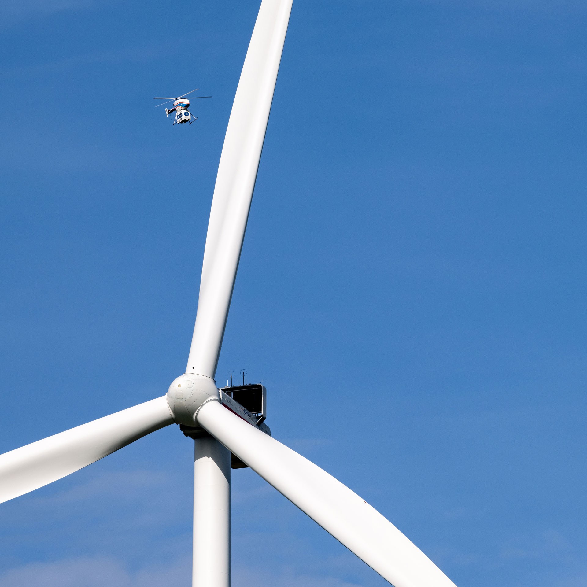 Der unbemannte DLR-Kleinhubschrauber superARTIS hat Informationen mit der Windenergieanlage ausgetauscht, damit er sich sicher nähern kann. Für ein realistisches Szenario im Projekt „Upcoming Drones Windfarm“ haben die Forschenden eine Traglast am Fluggerät befestigt.