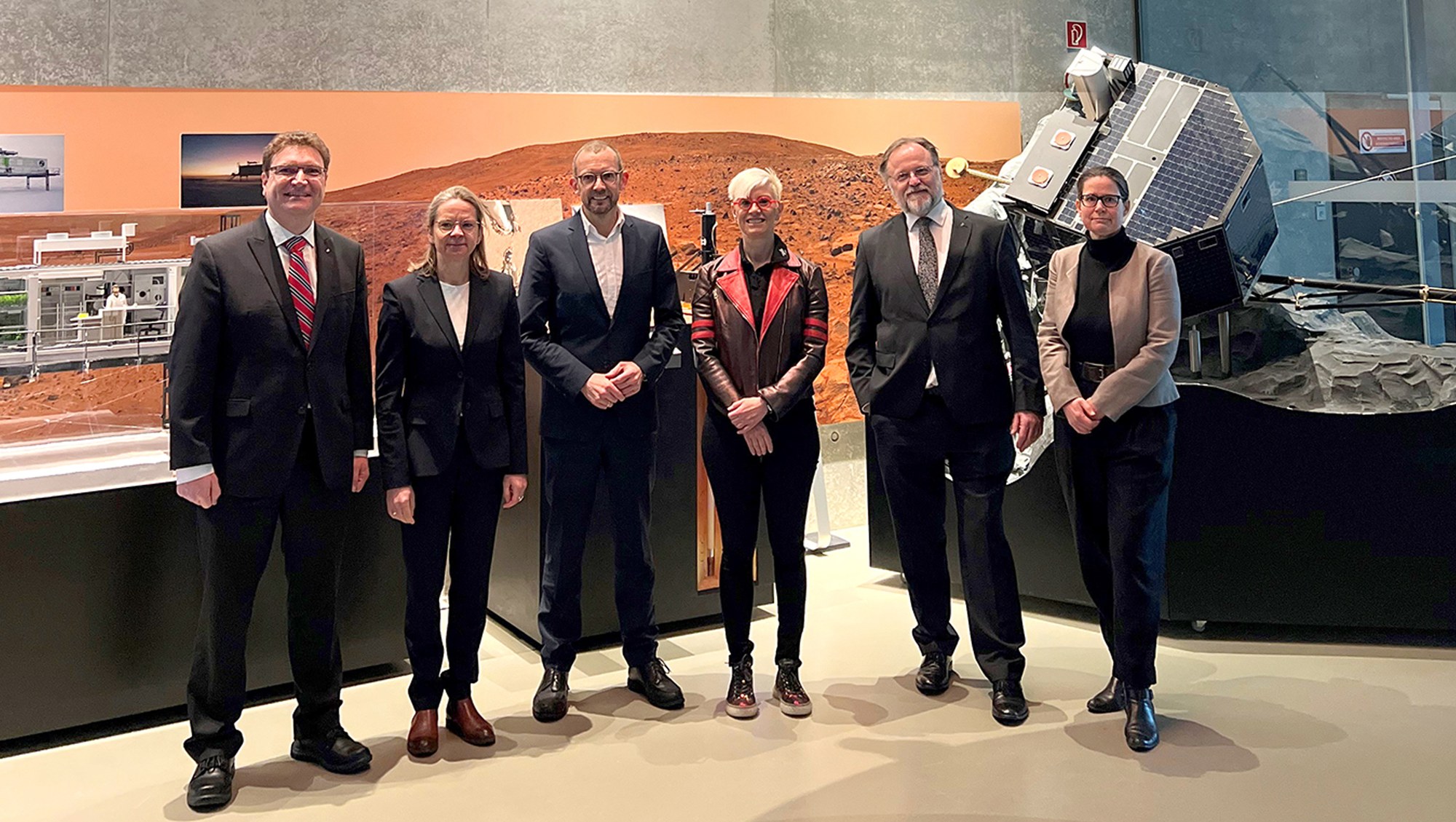 Mehrere Gäste, darunter der Bundestagsabgeordnete Thomas Röwekamp, und DLR-Mitarbeitende stehen im Foyer des DLR in Bremen