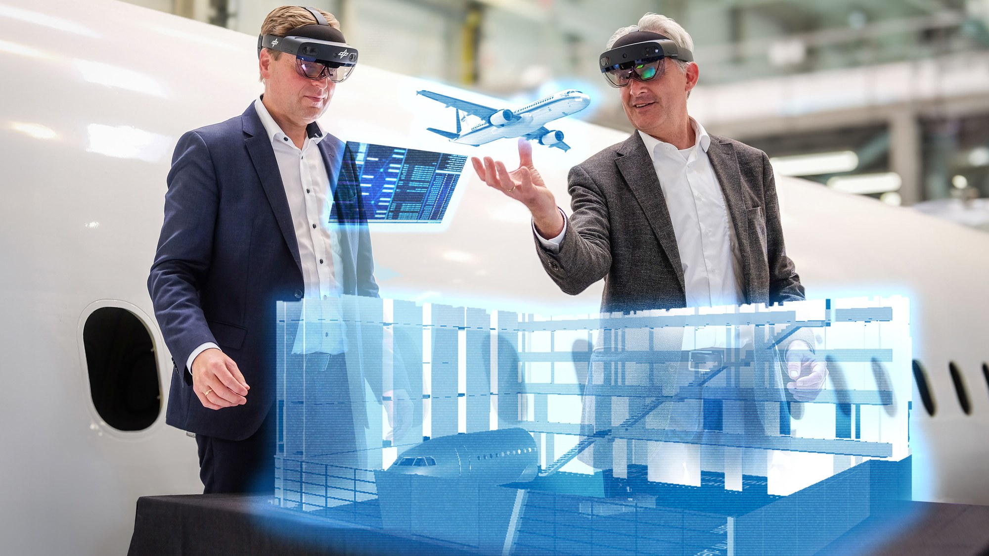 Prof. Björn Nagel, Direktor des DLR-Instituts für Systemarchitekturen in der Luftfahrt, und Prof. Gerko Wende, Direktor des DLR-Instituts für Instandhaltung und Modifikation, vor einem virtuellen Modell des ZAL-Anbaus in Hamburg-Finkenwerder.