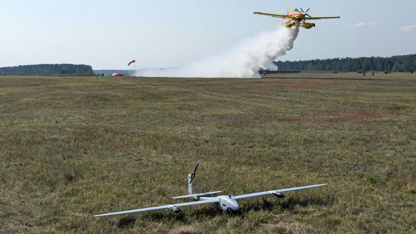 Ein Löschflugzeug überfliegt den Vegetationsbrand, nachdem die Drohne des DLR-Instituts für Optische Sensorsysteme sicher am Boden gelandet ist.