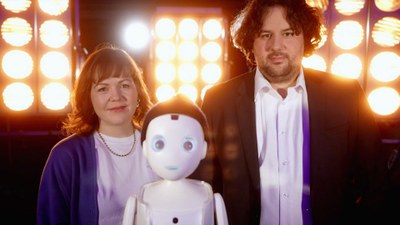 Das Bild zeigt zwei Mitarbeitende vom DLR-Institut für Softwaretechnologie und einen Roboter.