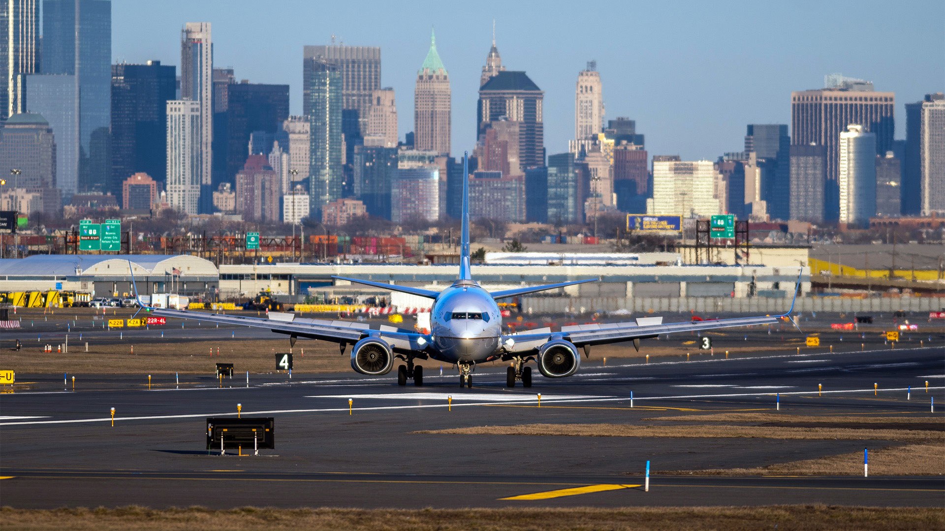 Symboldbild: Eine Passasgiermaschine auf dem Rollfeld des Newark Liberty International Airports. Im Hintergrund ist die Skyline von Manhatten zu sehen.