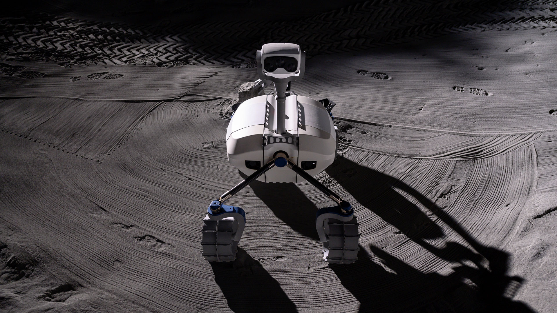 Das Bild zeigt einen weißen Roboter mit vier Rädern und einem Kamerasystem. Der Roboter LRU steht in der LUNA-Halle.