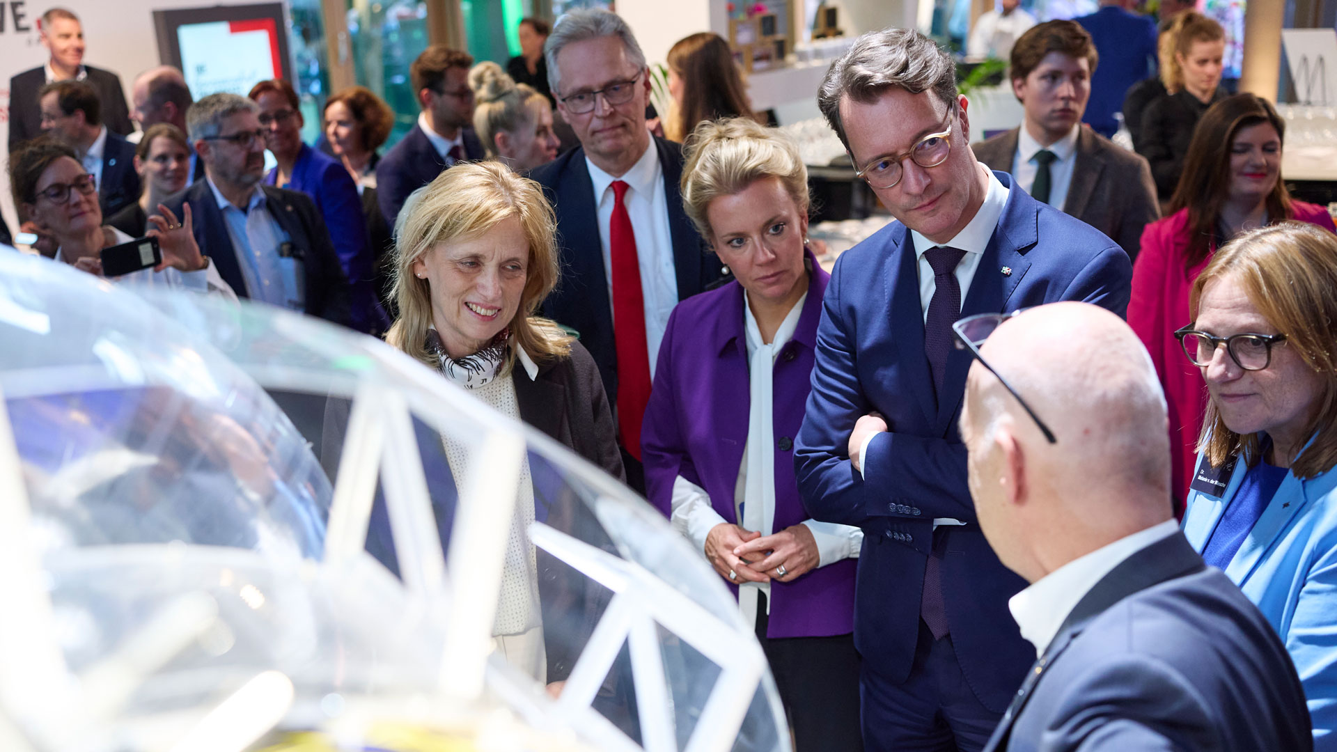 Bundesministerin Karin Prien, Prof. Karsten Lemmer, Mitglied des DLR-Vorstands und verantwortlich für das Ressort Innovation, Transfer und wissenschaftliche Infrastrukturen, Ministerin Ina Brandes, NRW-Ministerpräsident Hendrik Wüst sowie Dr. Melanie von der Wiesche, Leiterin DLR-Standorte West, im Gespräch mit DLR-Weltraumexperte Volker Schmid.
