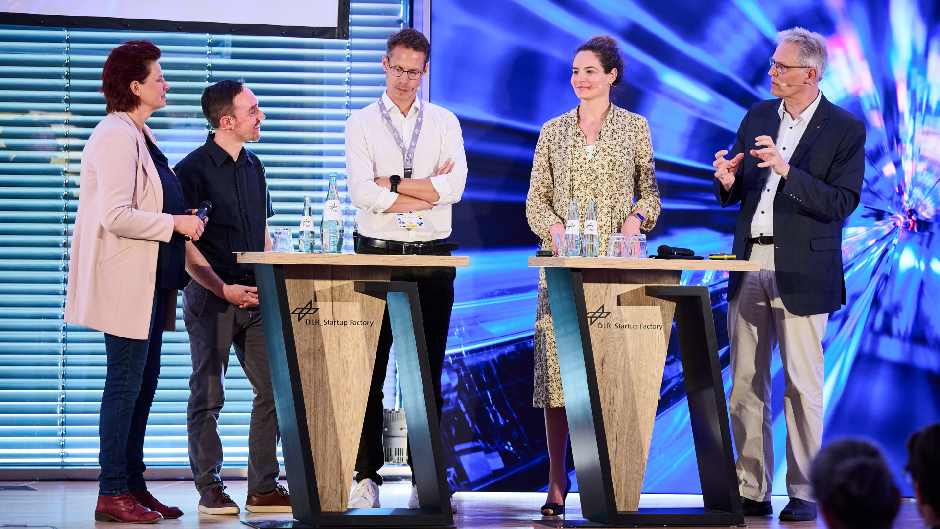 Fünf Personen stehen an einem großen Stehpult und diskutieren.