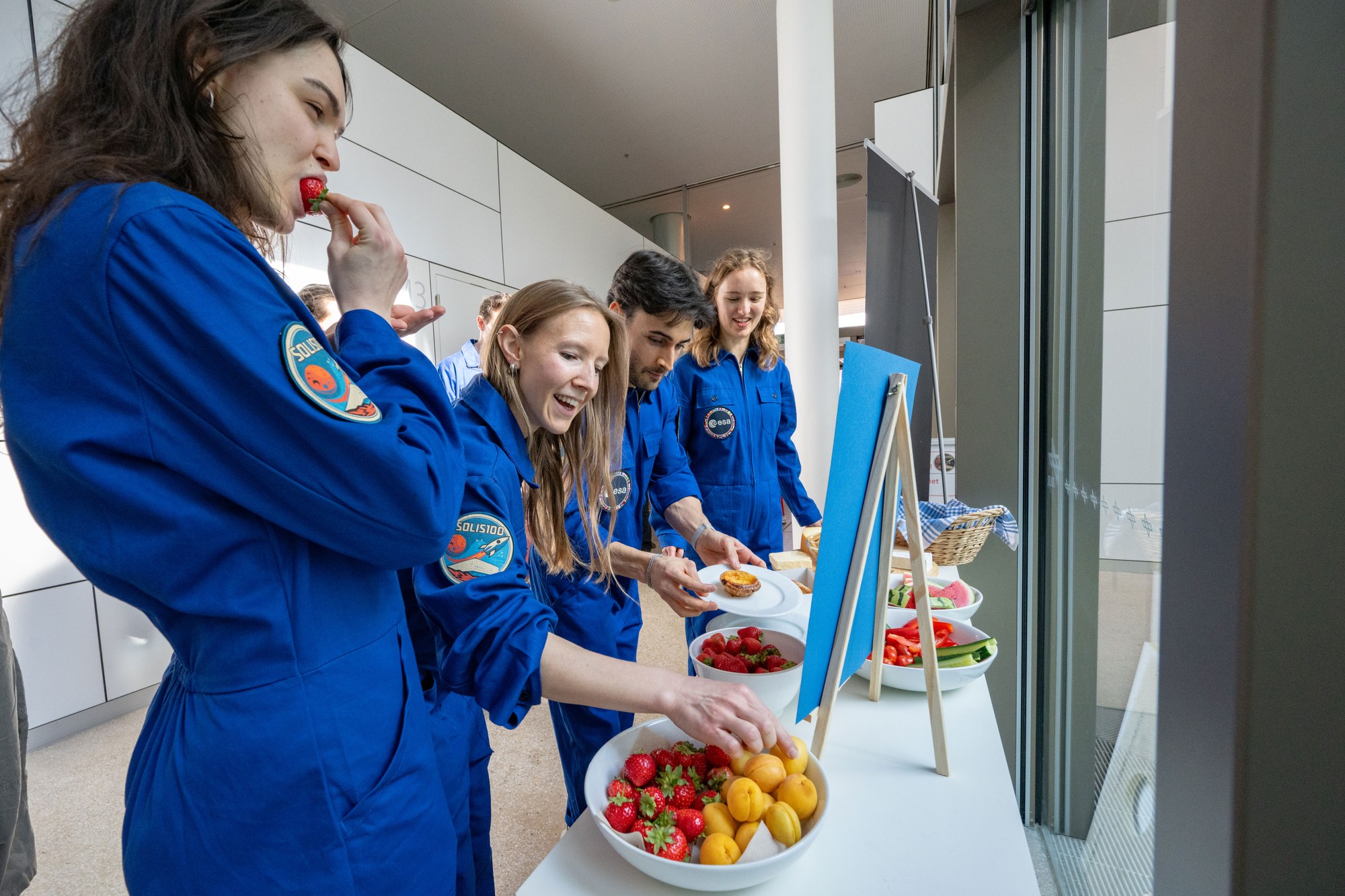 Mehrere Teilnehmende essen Obst, Gemüse und Gebäck und freuen sich über die frischen Lebensmittel.