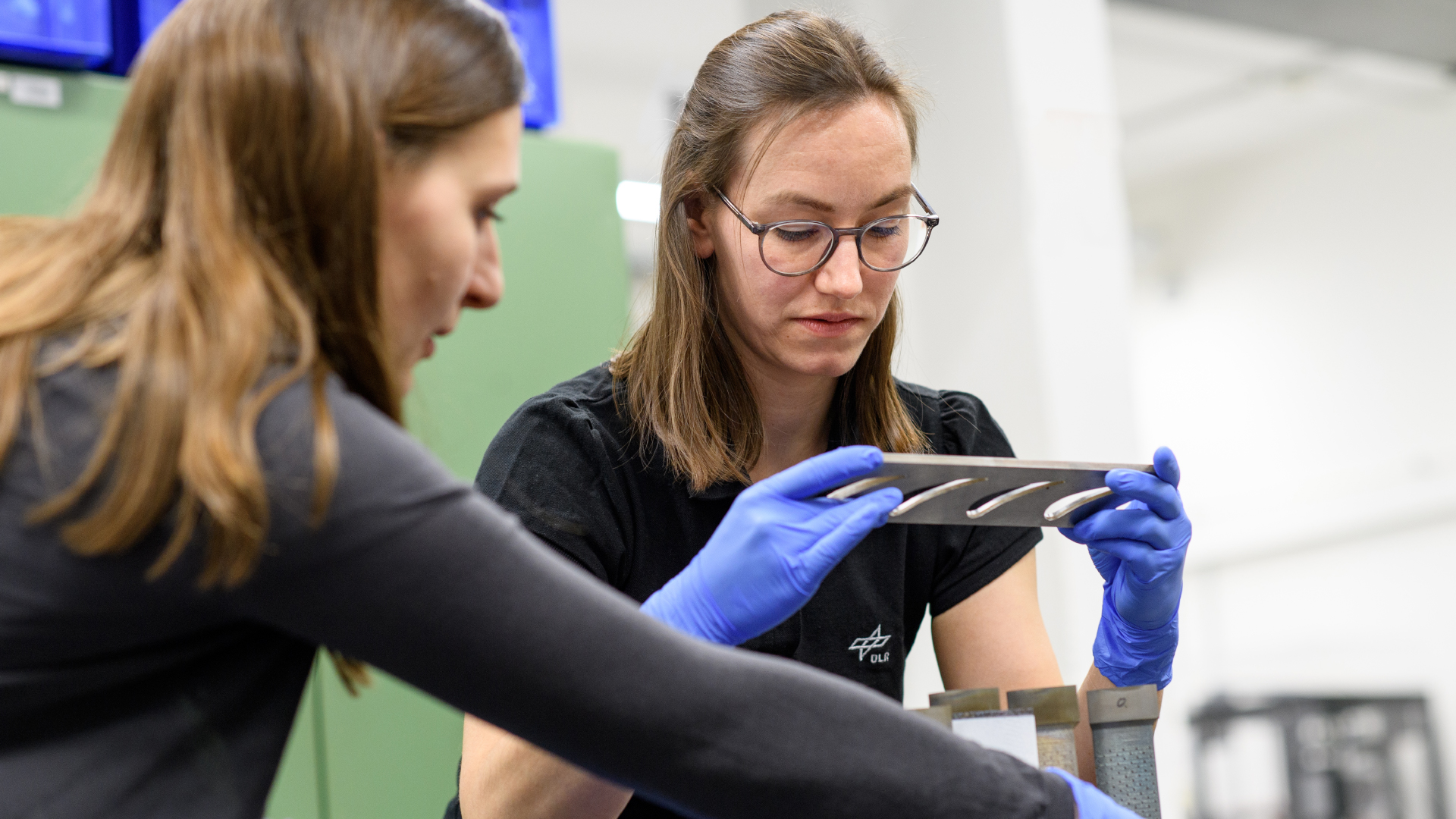 Projektleiterin Dr. Anna Petersen (links) vom DLR-Institut für Antriebstechnik und Fabia Süß vom DLR-Institut für Bauweisen und Strukturtechnologie bereiten die Versuche vor. Um die Kühleffizienz und die aerodynamische Leistung zu analysieren und zu bewerten, werden die Schaufeln im Windkanal für ebene Kaskaden Göttingen auf TRL 4 getestet.