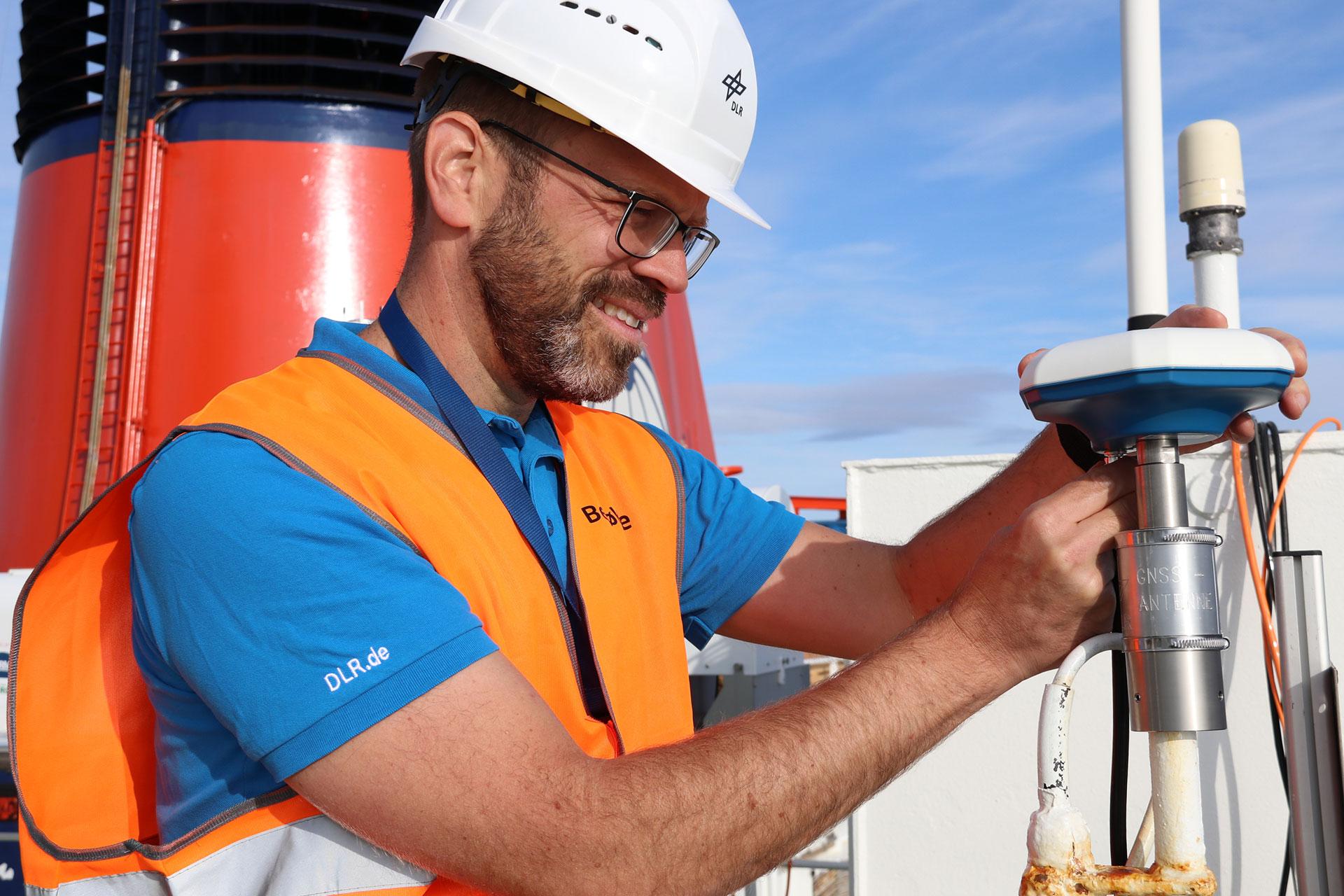 DLR-Projektleiter Plass befestigt die Empfangsantenne auf Peildeck der Polarstern