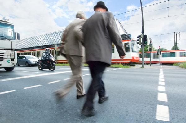 Zwei Personen überqueren eine Straße.