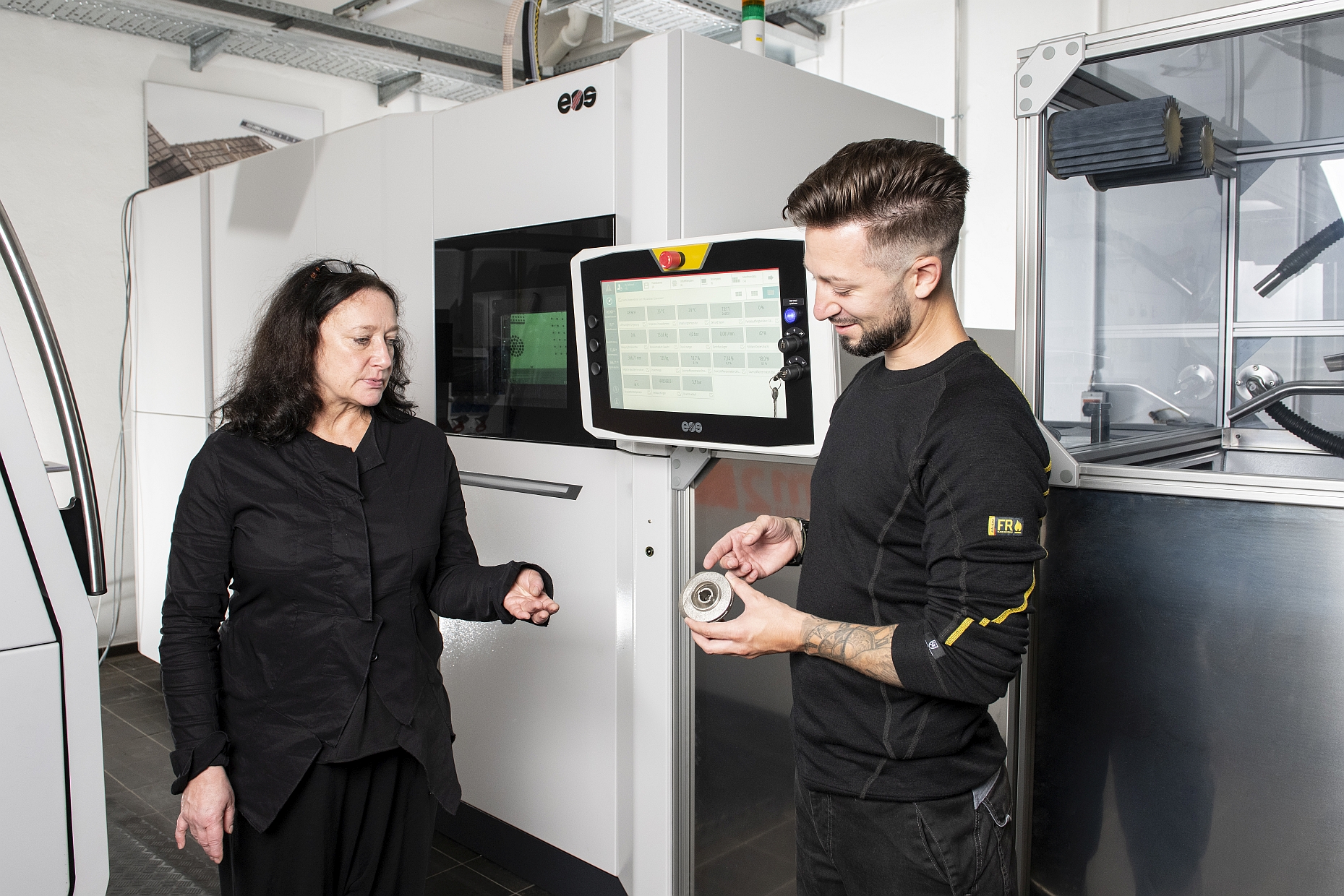 Zwei Mitarbeiter prüfen 3D-gedruckte Testbauteile