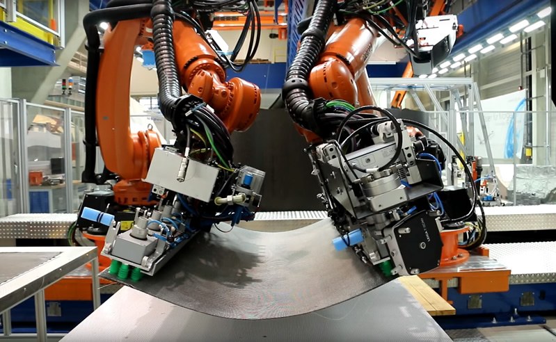 Zwei kollaborierende Roboter beim Transport eines CFK-Zuschnitts
