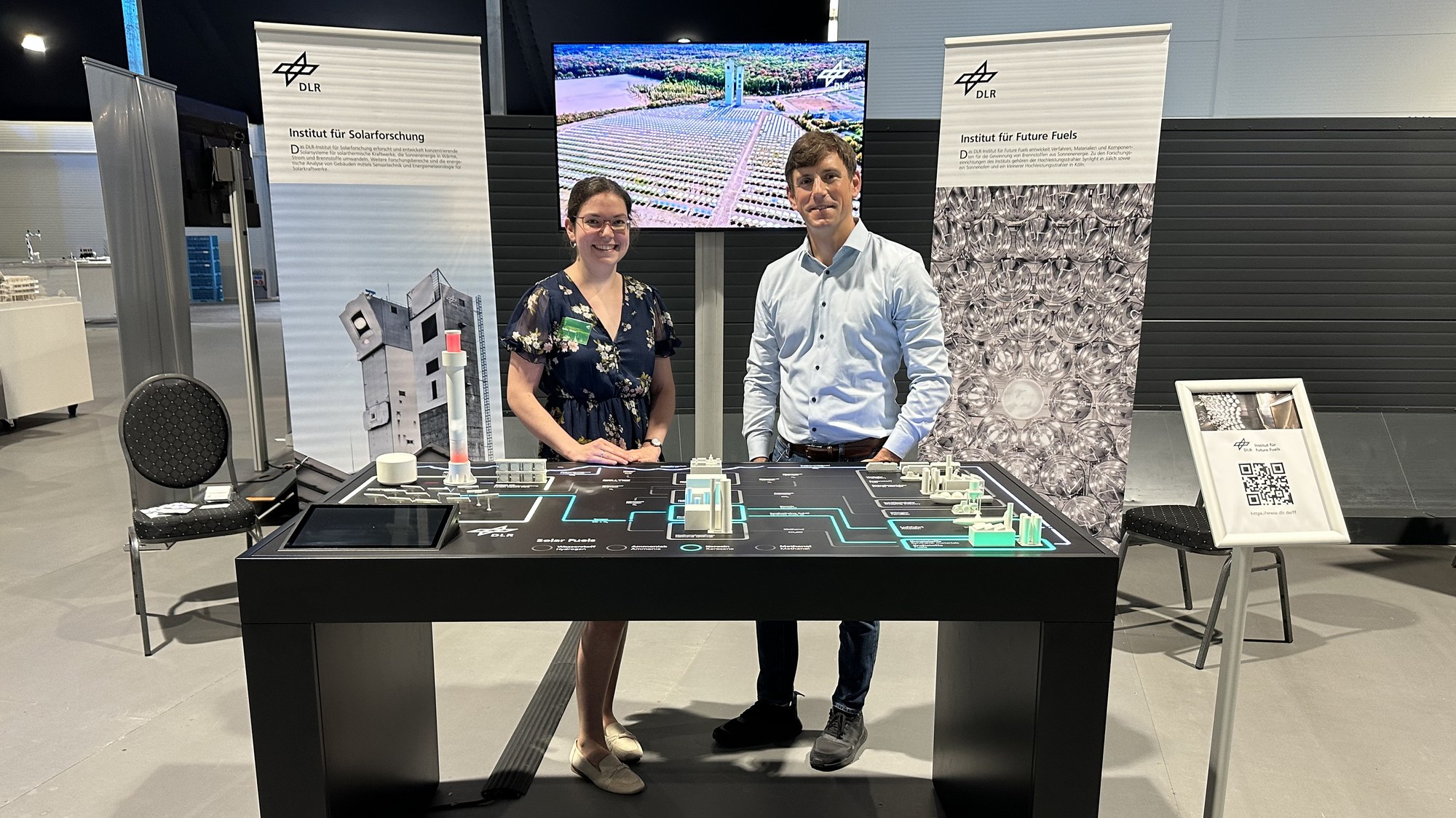 Zwei Forschende des Instituts stehen hinter dem Exponat Solar Fuels am DLR-Stand der Wasserstoff-Messe.