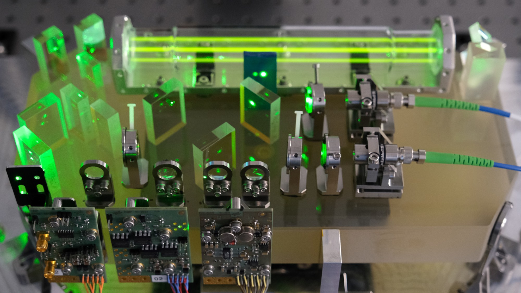 Grün leuchtender Laserstrahl der DLR-Laseruhr mit Jodgaszelle und Optikbauteilen