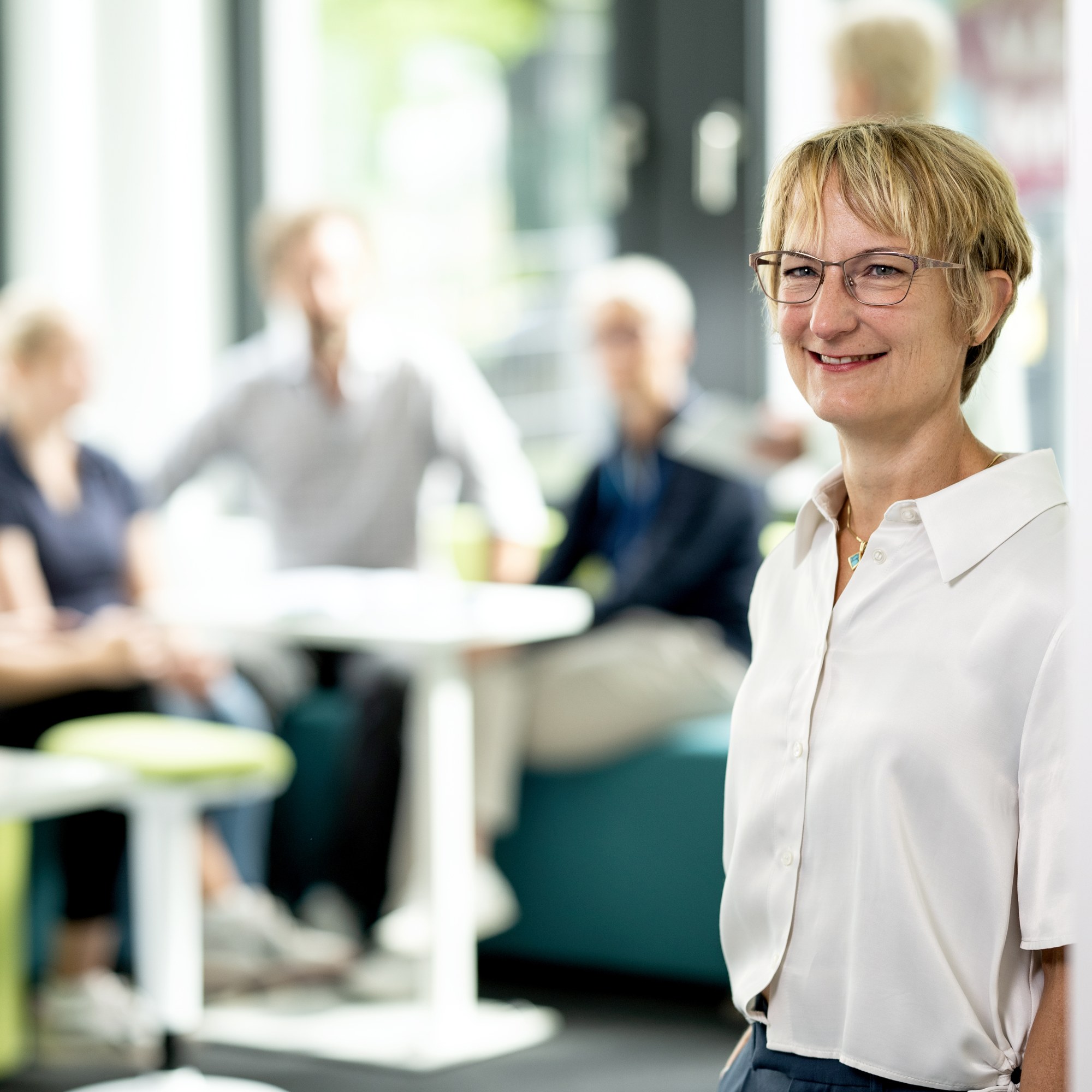 Im Vordergrund ist eine Mitarbeitende des DLR Projektträgers zu sehen. Im Hintergrund sind mehrere Mitarbeitende verschwommen erkennbar.