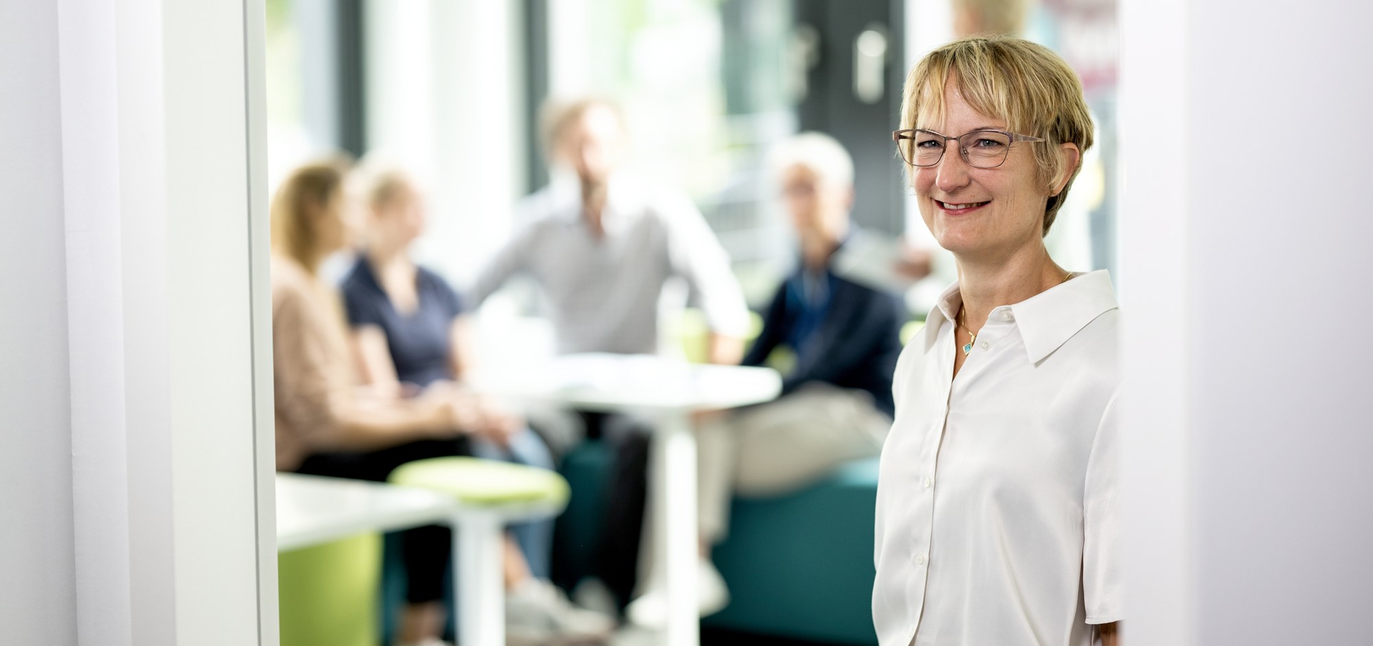 Im Vordergrund ist eine Mitarbeitende des DLR Projektträgers zu sehen. Im Hintergrund sind mehrere Mitarbeitende verschwommen erkennbar.
