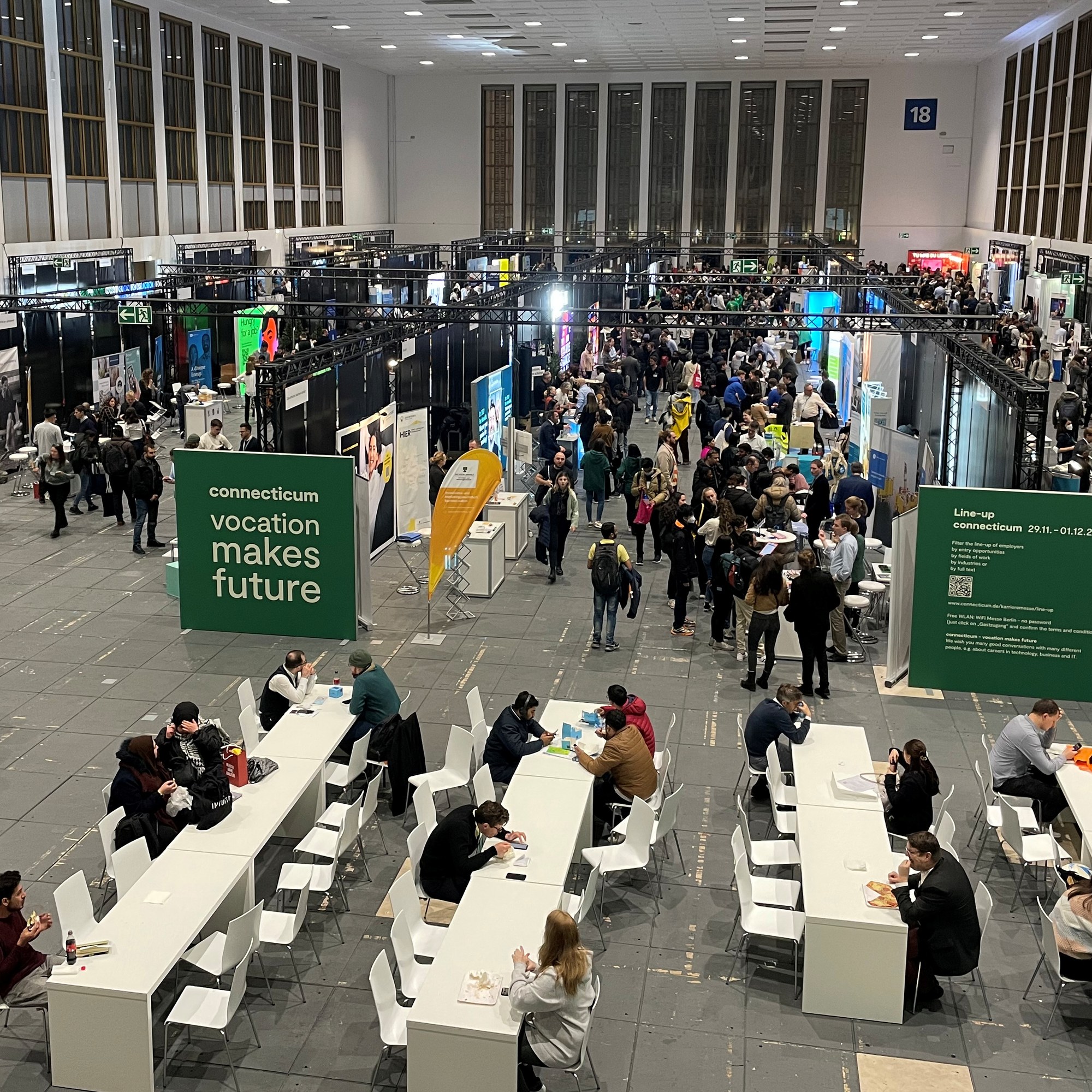 Überblick einer Karriereveranstaltung im Rahmen der Connecticum Berlin. Viele Messestände und Besucher/innen sind zu erkennen.
