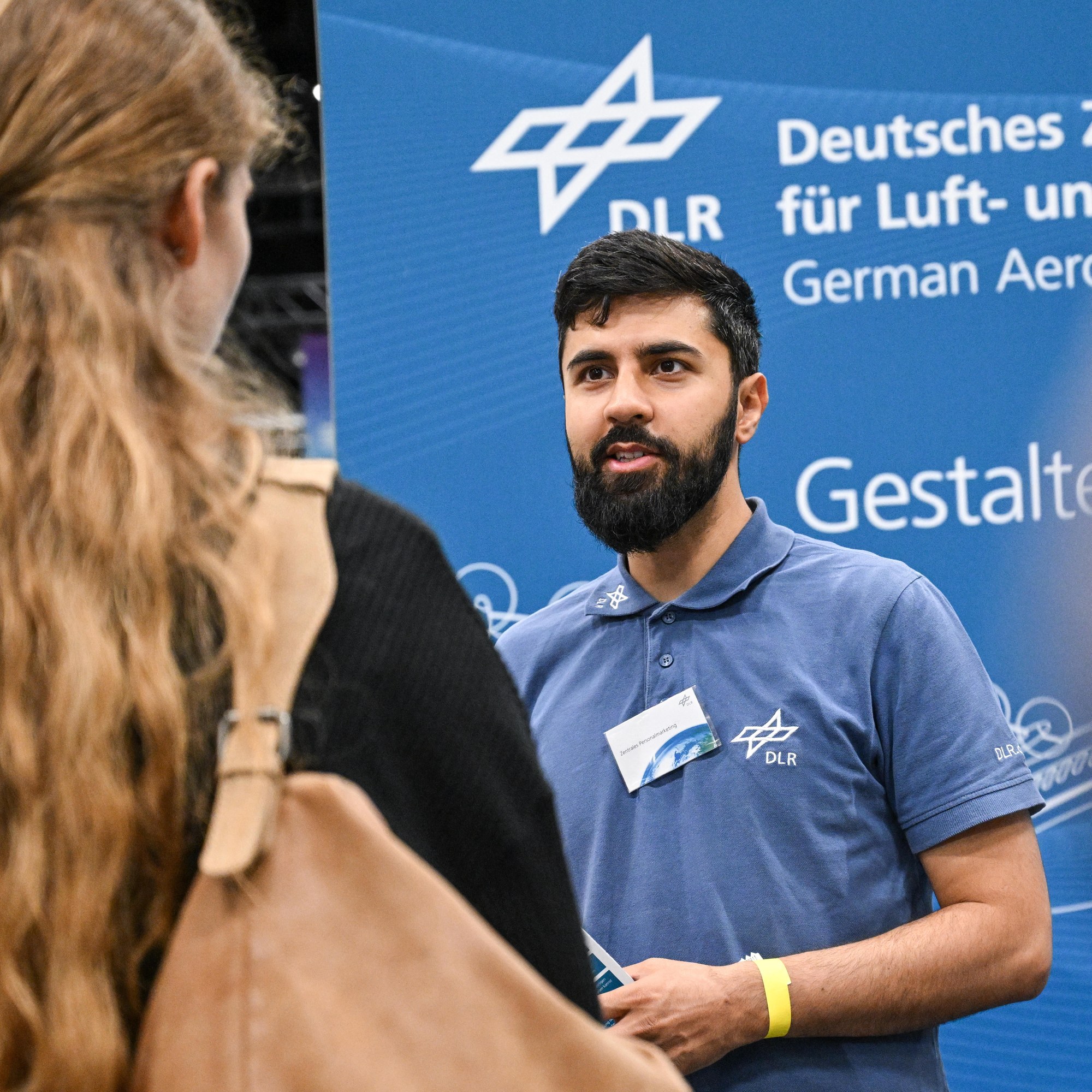 Ein DLR-Mitarbeiter im Gespräch mit einer Interessentin auf einer Karrieremesse.
