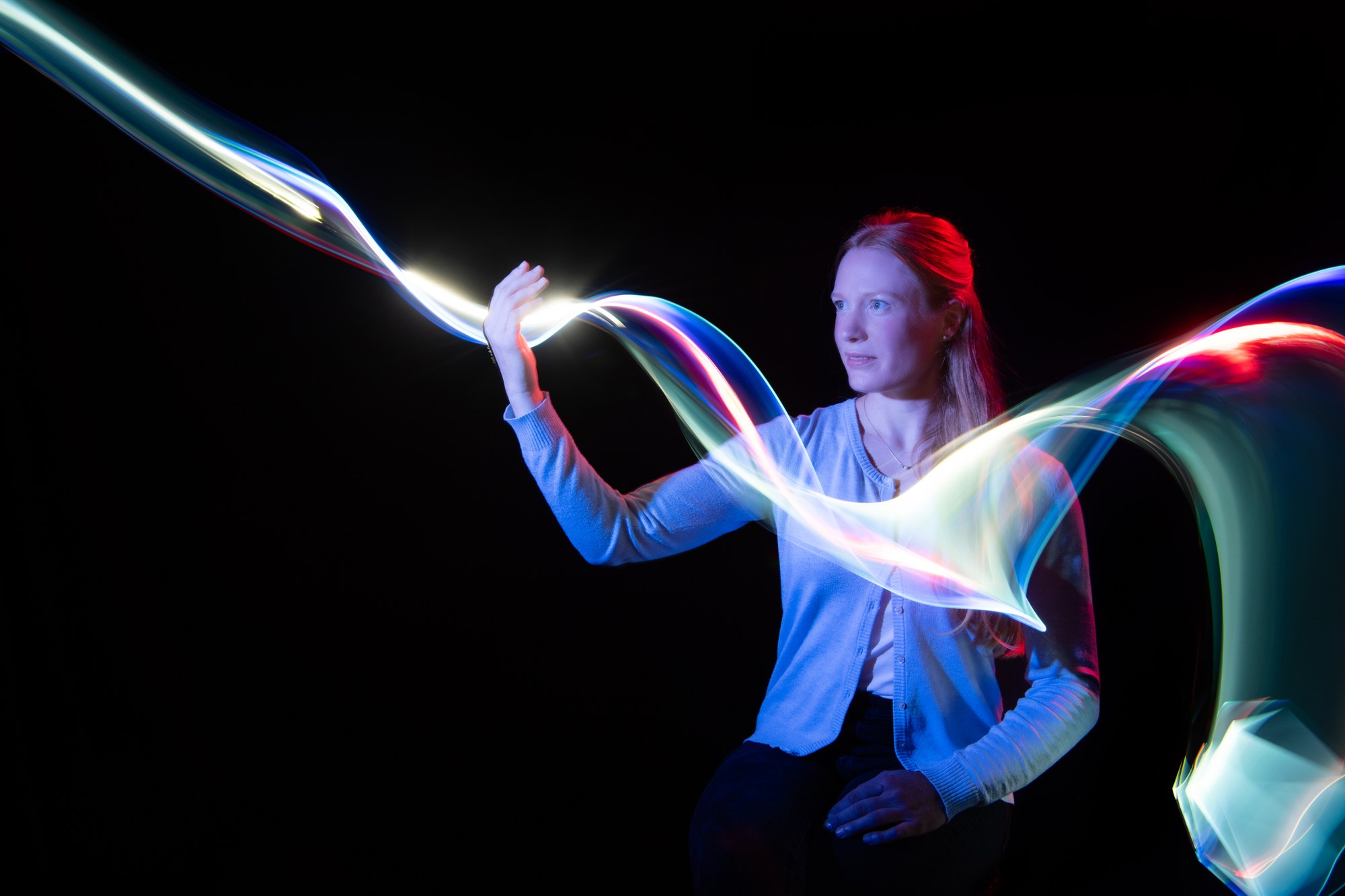 Das Bild zeigt DLR-Mitarbeiterin Celia und leuchtende Lichtspuren