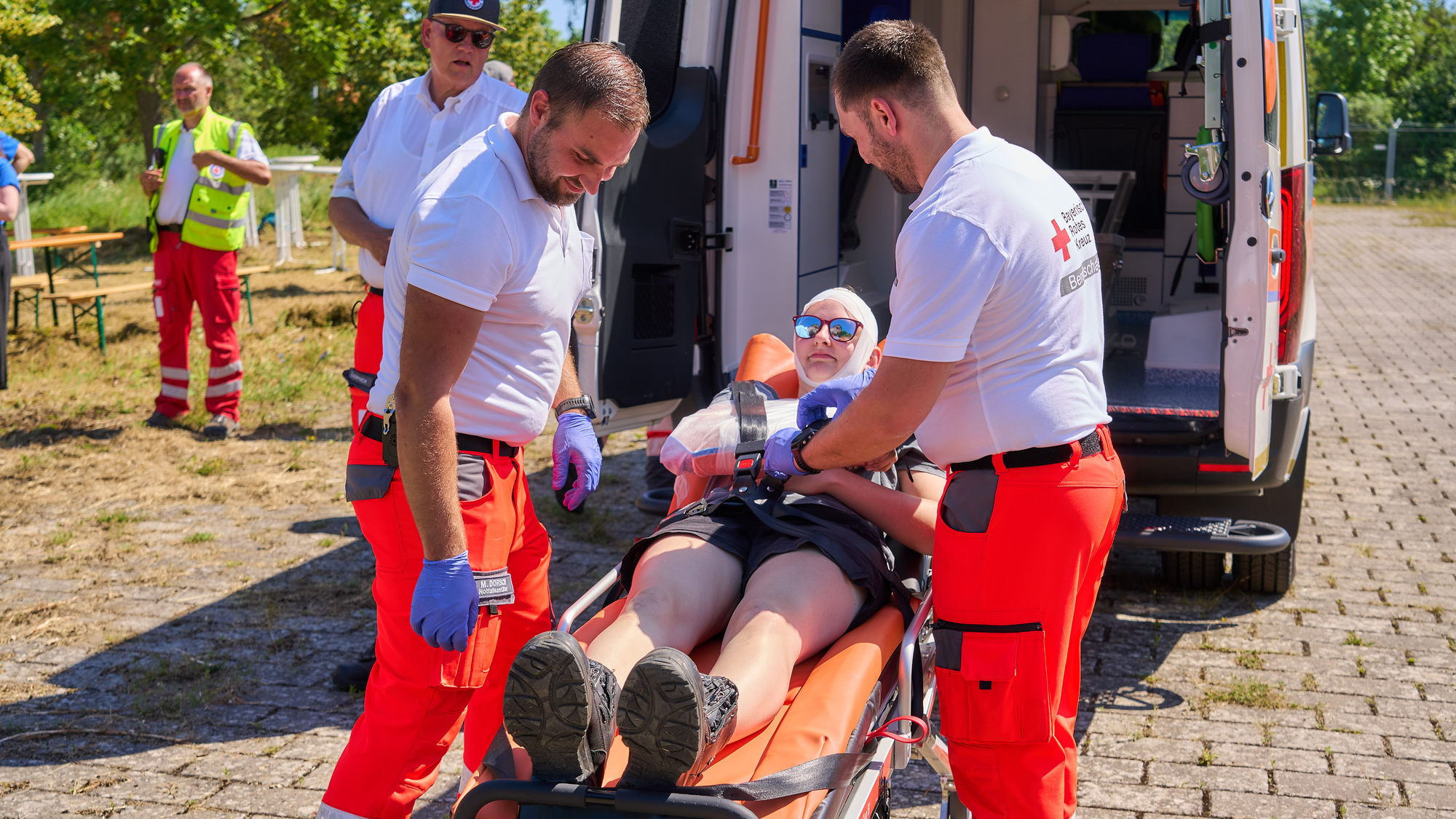 Eine verletzte Person liegt auf einer Trage und wird von zwei Sanitätern versorgt.