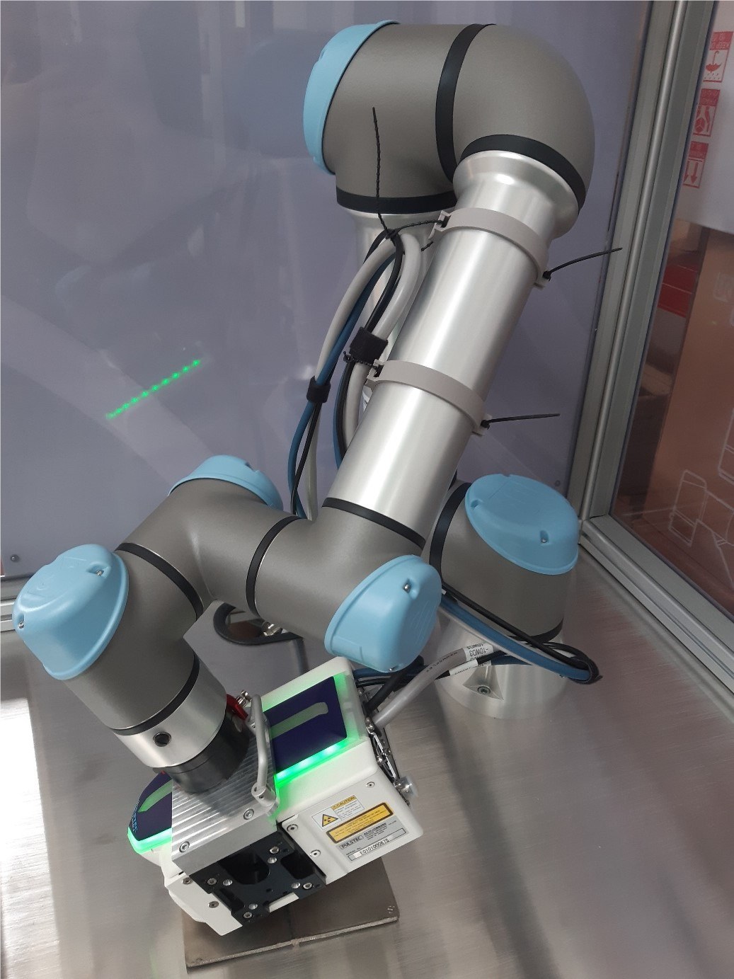Ein Roboterarm in einem Glaskasten, der ein Messgerät führt.