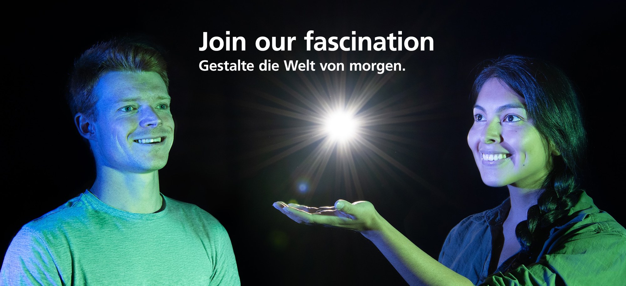 Es sind zwei Mitarbeitende des DLR abgebildet. Links: Cedric, rechts: Gabriela. Sie lächeln und schauen auf einen Lichtstrahl. Über Ihnen steht: Join our Fascination Gestalte die Welt von morgen.