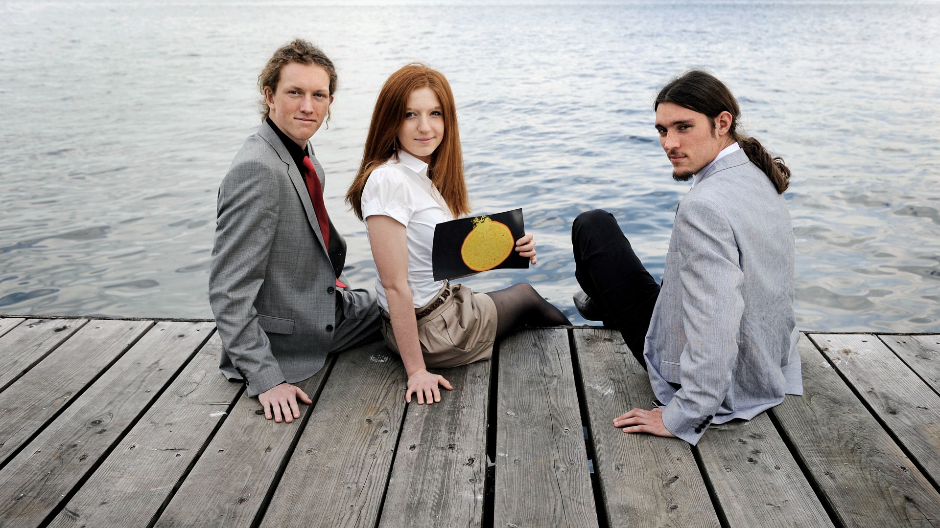 Drei Schülerinnen sitzen an einem Steg