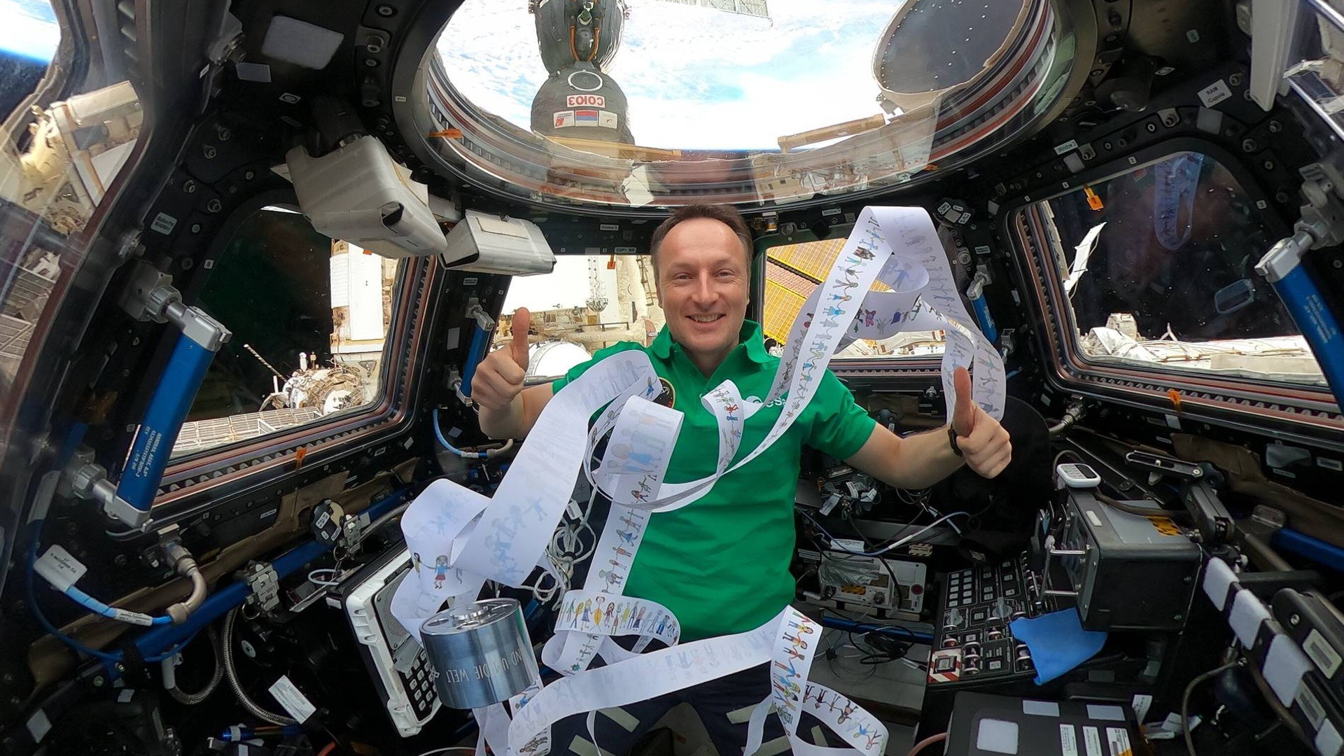 Matthias Maurer mit dem Bilderstreifen im Cupola-Modul der ISS.