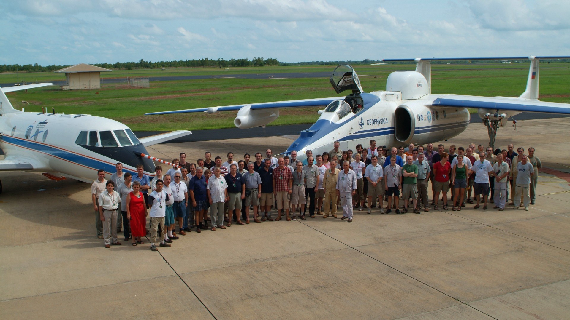 Gruppenbild, Menschen mit Flugzeug im Hintergrund
