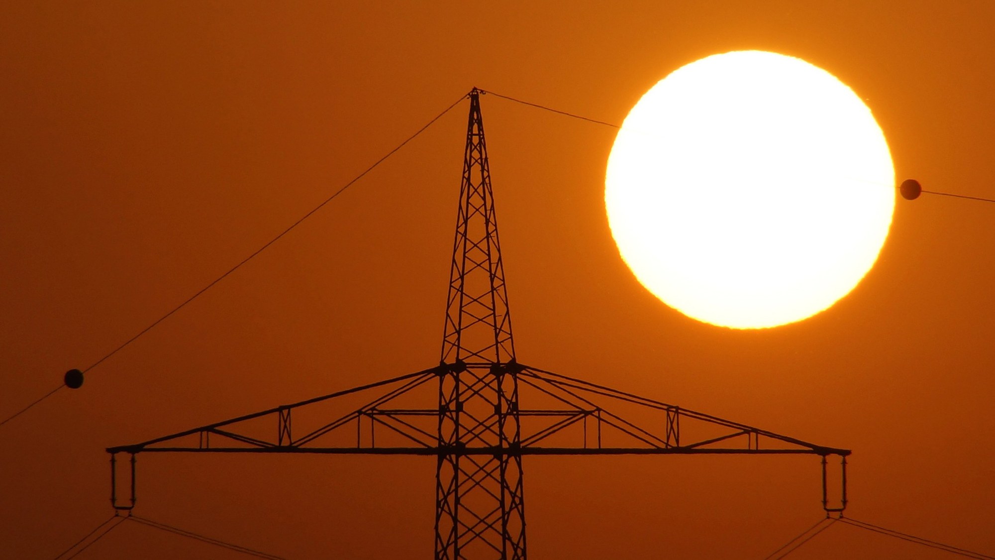 Sonne hinter Hochspannungsmast