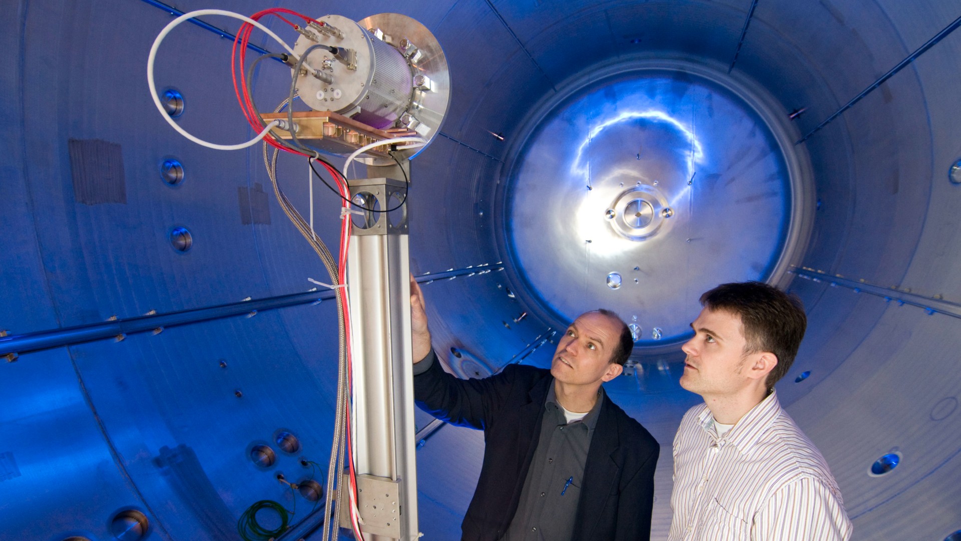 Zwei DLR-Wissenschaftler bereiten den Test eines Satellitentriebwerks in einer Vakuumkammer vor.