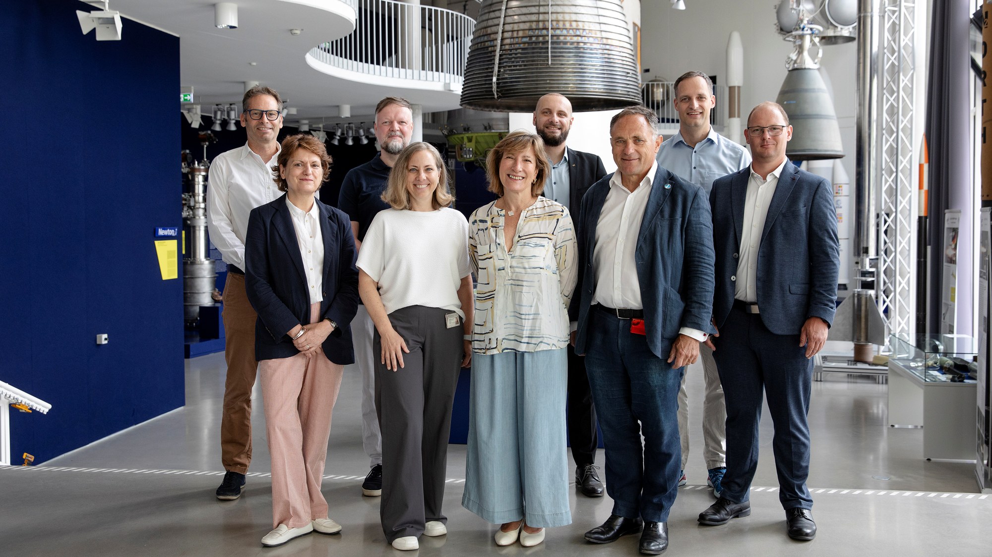 Das Bild zeigt die Delegation der Europäischen Weltraumorganisation ESA gemeinsam mit Vertreterinnen und Vertretern der DLR-Einrichtung Raumfahrtantriebe in der Ausstellung des DLR-Forums für Raumfahrtantriebe am Standort Lampoldshausen.