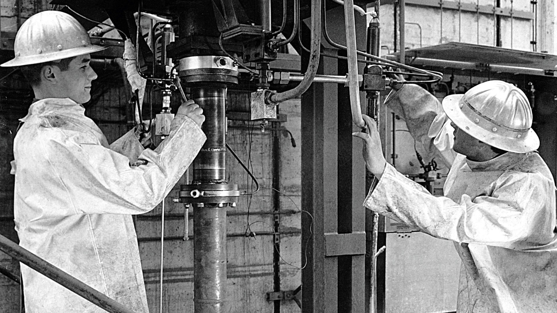 Das Bild zeigt zwei Personen, die Montagearbeiten an einem Prüfstand durchführen.