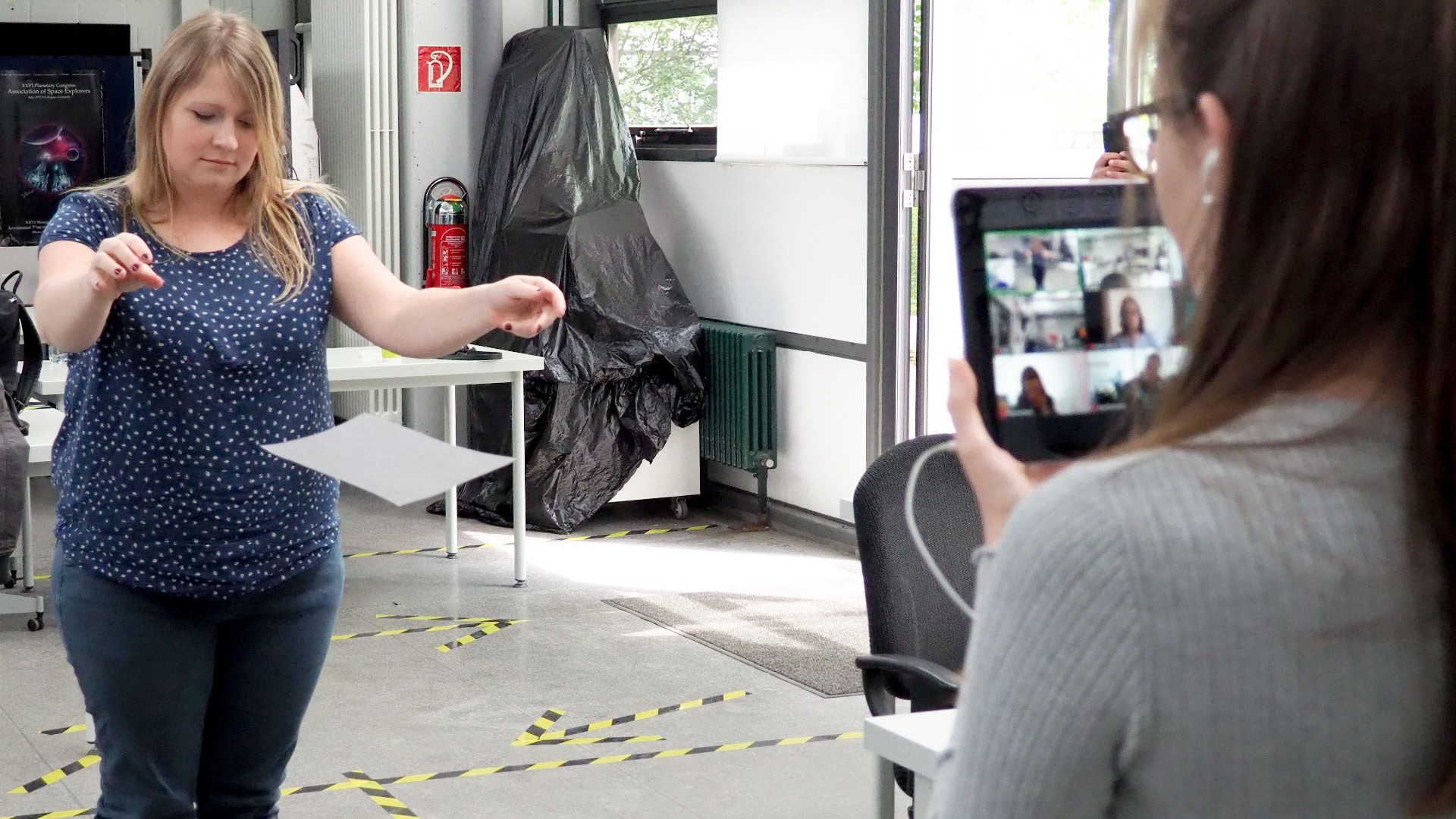 Teilnehmerin beim Experiment zwei Blätter Papier im Freien Fall