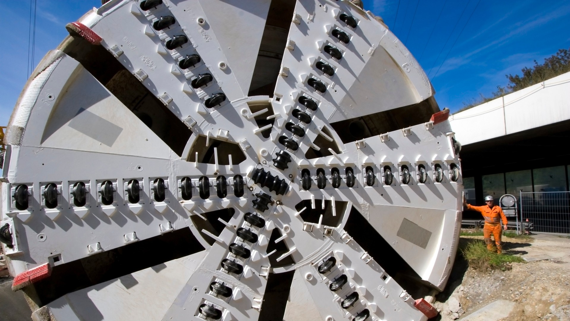 Bohrkopf einer Tunnelbohrmaschine im Größenvergleich zu einem Menschen