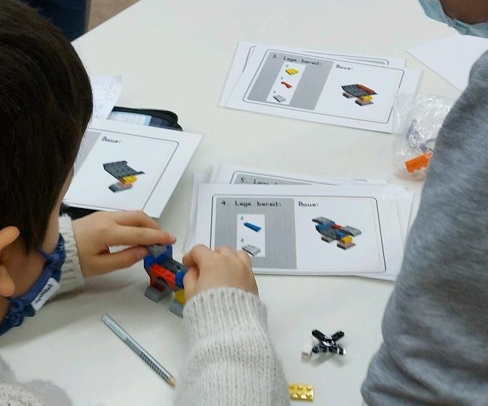 Grundschulkinder bauen einen Roboter aus Lego®-Steinen.