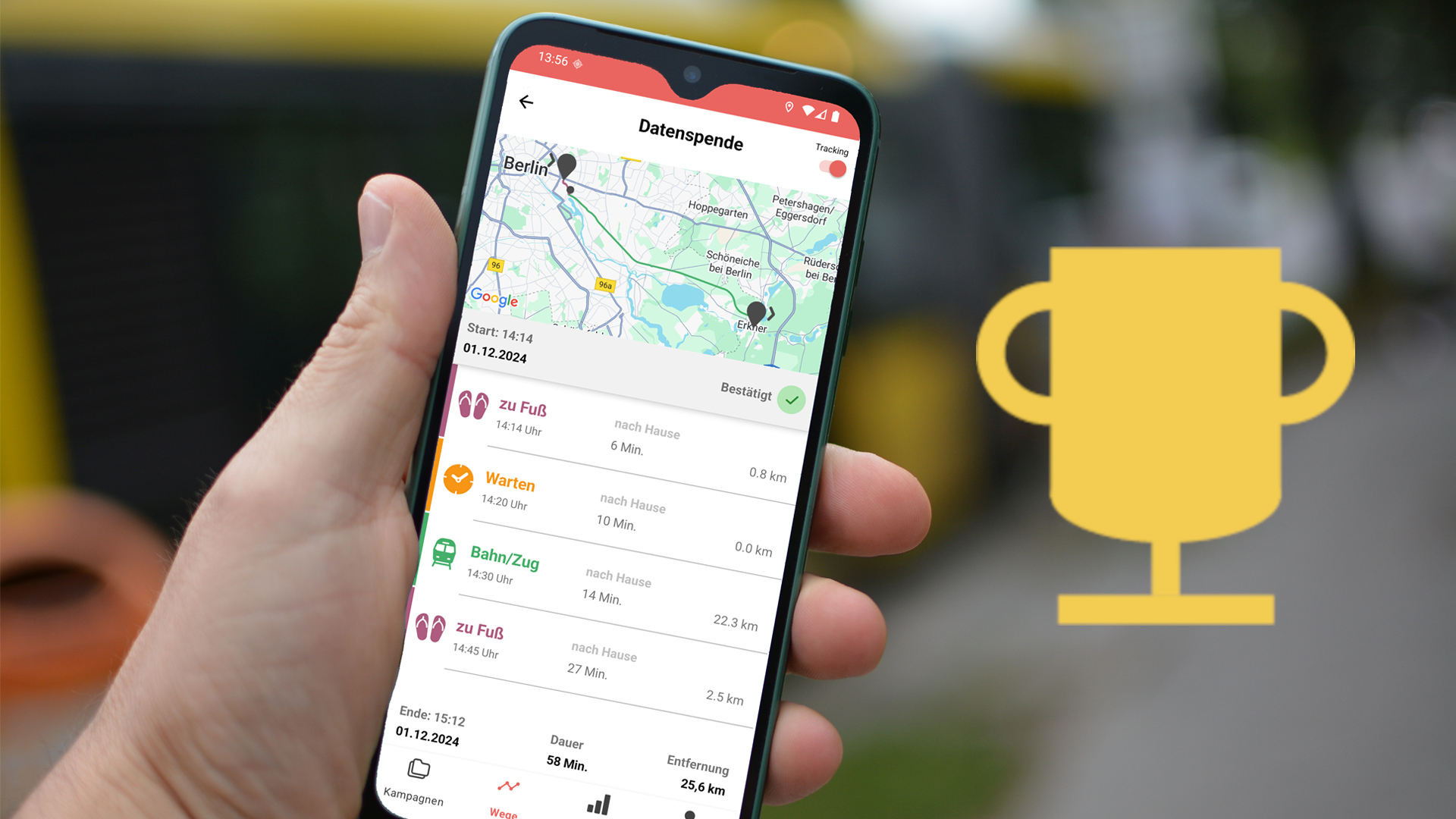 Zu sehen ist, wie jemand ein Smartphone mit der MovingLab App in einer Hand hält. Im Hintergrund ist eine befahrene Straße zu sehen. Auf der rechten Seite des Bildes wird ein stilisierter Gewinnerpokal gezeigt.
