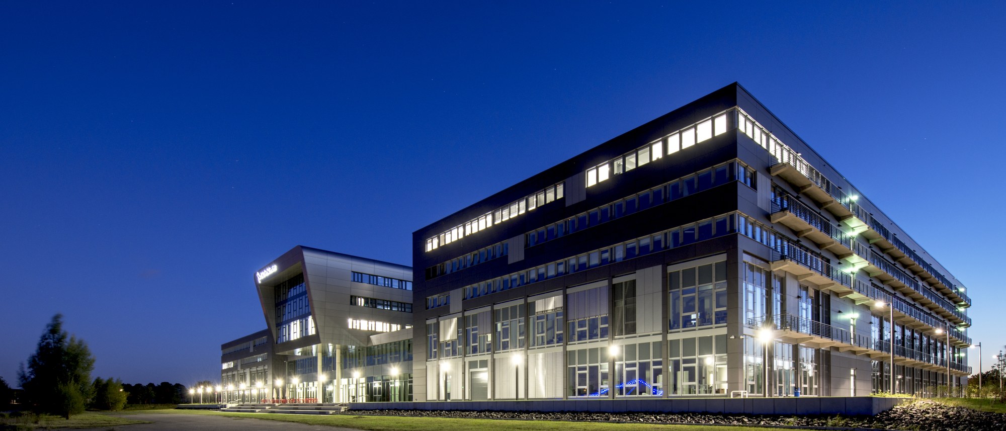 Ein Bild des ZAL TechCenters, eines modernen Bürokomplexes, bei Nacht aufgenommen, mit Beleuchtung in einigen Büros.