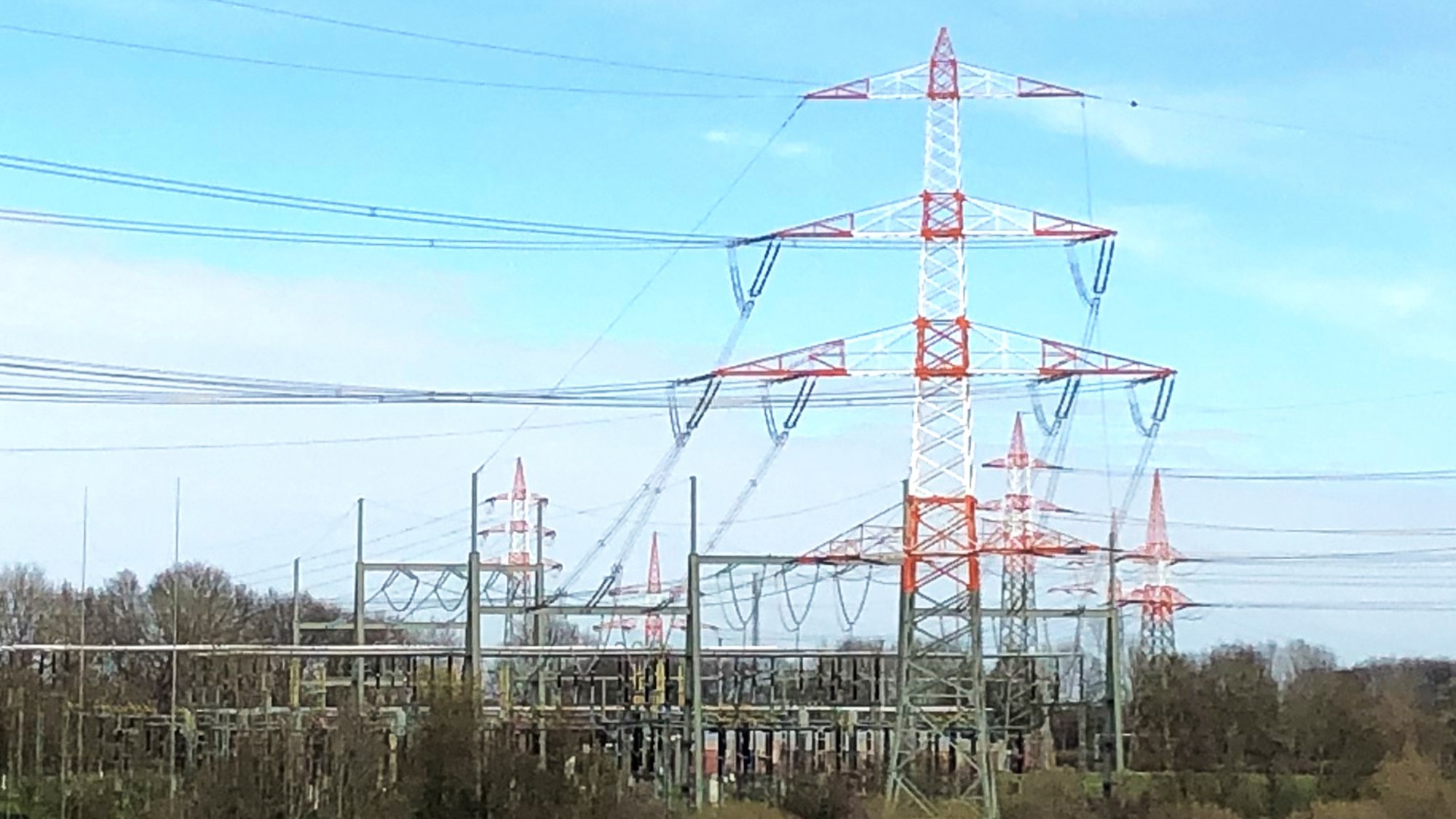 Strommast mit Stromleitungen, die zu einem Umspannungswerk führen.