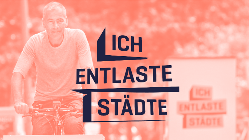 Das Bild zeigt ein Foto mit einem Mann, der auf einem Lastenfahrrad fährt. Im Hintergrund ist das Logo "ICH ENTLASTE STÄDTE"