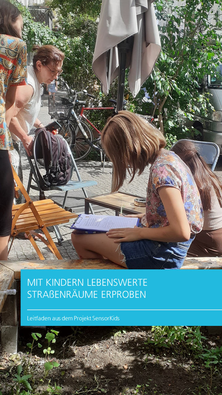 Kinder sitzen bei einem Bepflanzungsstein und füllen eine Umfrage aus.