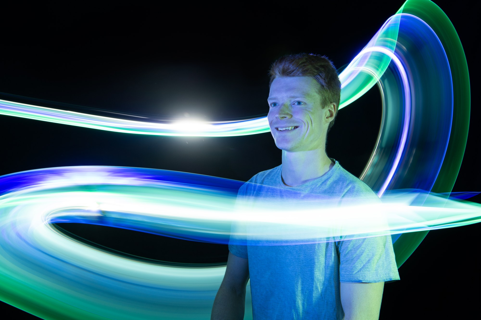 The picture shows Cédric, a member of staff, and colourful trails of light